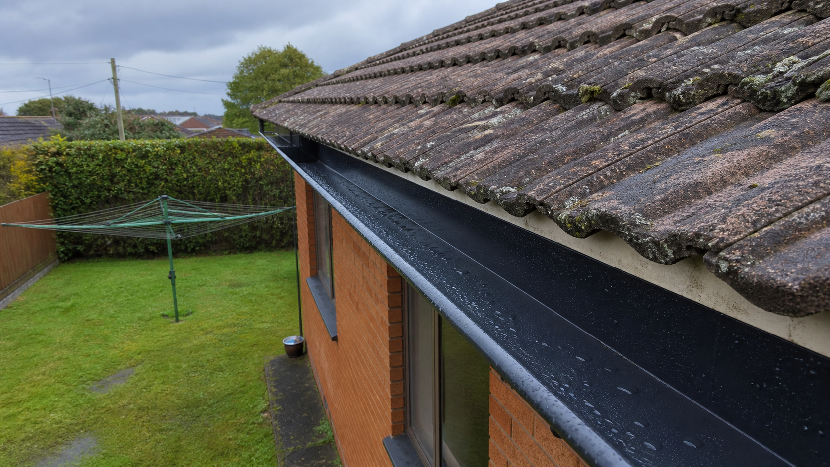 Newly cleaned black gutter beside an older Hamilton tile roof